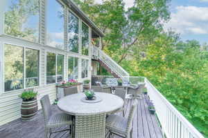 Wooden terrace featuring outdoor dining area and stairway