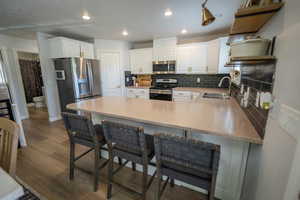 Kitchen with newer stainless steel appliances, new faucet, new black subway tile backsplash, and a breakfast bar