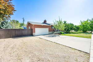 View of home's exterior featuring driveway, an attached garage, and a chimney
