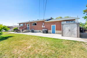 Back of property featuring a patio area, a yard, brick siding, and central AC