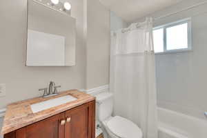 Bathroom with toilet, shower / bath combo, vanity, and wainscoting
