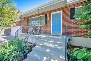 Doorway to property featuring brick siding, an attached garage, driveway, and a porch