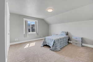 Carpeted bedroom with vaulted ceiling and baseboards
