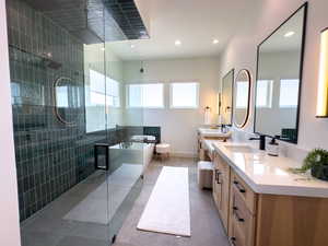 Bathroom featuring healthy amount of natural light, a soaking tub, double vanity, a shower stall, and recessed lighting