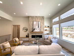 Living room featuring wood finished floors, recessed lighting, a stone fireplace, and baseboards