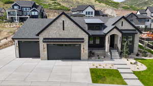 View of front facade featuring stone siding, driveway, an attached garage, a mountain view, and metal roof