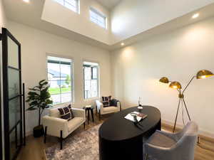 Living room featuring wood finished floors, baseboards, recessed lighting, and a towering ceiling
