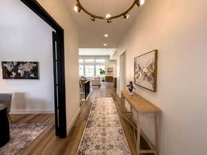 Hall with wood finished floors, recessed lighting, a chandelier, and baseboards