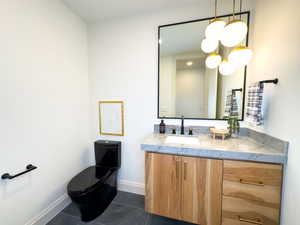 Half bath featuring tile patterned flooring, vanity, baseboards, and toilet