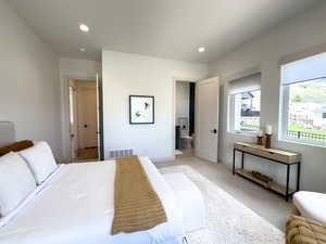 Bedroom featuring recessed lighting, baseboards, light colored carpet, and connected bathroom