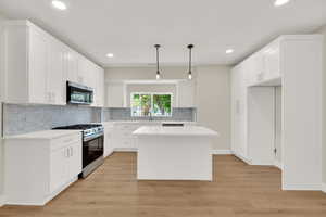 Kitchen featuring stainless steel appliances, a sink, decorative backsplash, light countertops, and recessed lighting