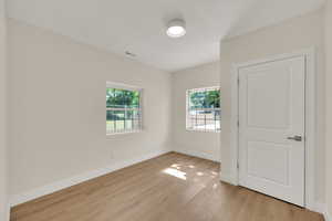 Spare room with healthy amount of natural light, light wood-style floors, and baseboards