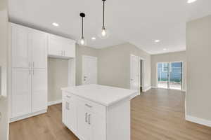 Kitchen featuring light wood-style flooring, baseboards, white cabinets, recessed lighting, and decorative light fixtures