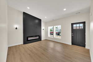 Unfurnished living room featuring a fireplace, plenty of natural light, baseboards, light wood-style flooring, and recessed lighting