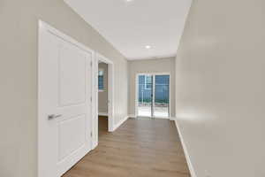 Corridor with baseboards, light wood finished floors, and recessed lighting