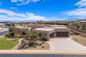 Pueblo revival-style home featuring an attached garage, stucco siding, a mountain view, and concrete driveway