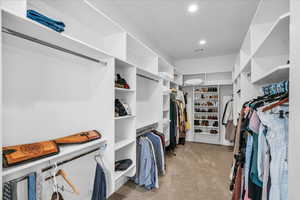 Walk in closet with light colored carpet