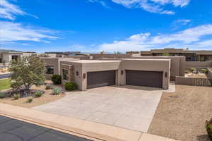Pueblo revival-style home with stucco siding, an attached garage, and driveway