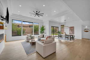 Living area with a glass covered fireplace, light wood-style flooring, ceiling fan, and recessed lighting