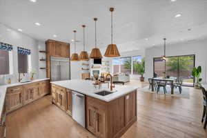 Kitchen featuring a sink, open shelves, appliances with stainless steel finishes, a center island with sink, and recessed lighting