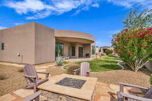 Back of property with a fire pit, stucco siding, a patio, and a yard