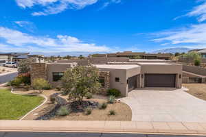 Pueblo-style house featuring a garage, stucco siding, a mountain view, and driveway