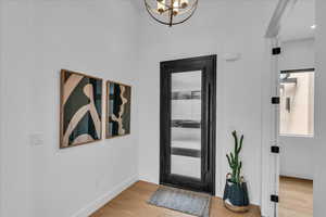 Foyer entrance featuring wood finished floors, baseboards, and a chandelier