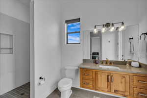Ensuite bathroom featuring vanity, tile patterned floors, tiled shower, and toilet