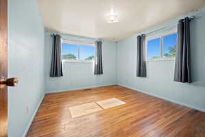 Spare room featuring plenty of natural light, wood-type flooring, and baseboards