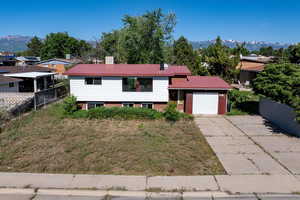 View of front facade with an attached garage, driveway, a mountain view, and metal roof