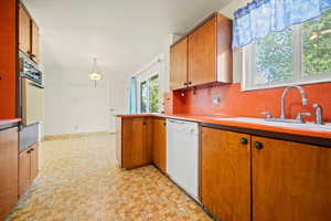 Kitchen with white appliances, a warming drawer, a sink, light countertops, and tasteful backsplash