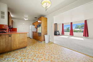 Kitchen featuring white appliances, a wood stove, brown cabinets, a sink, and open floor plan