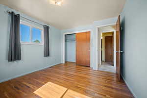 Unfurnished bedroom featuring wood finished floors, baseboards, and a closet