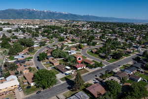 Aerial view of property and surrounding area featuring a mountainous background and nearby suburban area