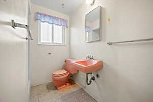 Full bathroom with toilet, a shower, baseboards, and a sink