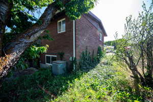 View of property exterior featuring brick siding and central AC unit