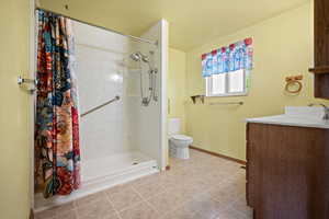 Bathroom with toilet, vanity, a shower with curtain, and baseboards