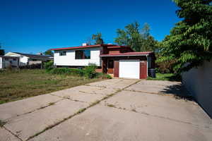 Tri-level home with driveway, an attached garage, and a chimney