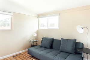 Living area featuring vaulted ceiling, healthy amount of natural light, wood finished floors, and baseboards