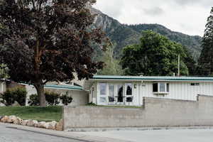 View of front of property with board and batten siding, a mountain view, metal roof, and a front lawn