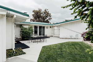View of grassy yard featuring a patio and a gate