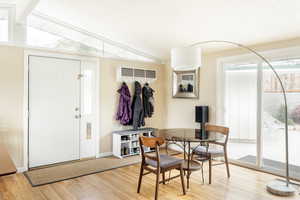 Dining area featuring light wood finished floors, healthy amount of natural light, lofted ceiling, and baseboards