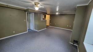 Finished basement with baseboards, a ceiling fan, and ornamental molding