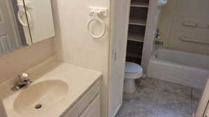 Full bathroom with toilet, vanity, tile patterned floors, and shower / bath combination