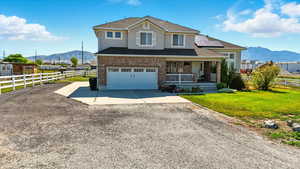 Traditional-style house featuring a mountain view, driveway, a porch, solar panels, and a garage