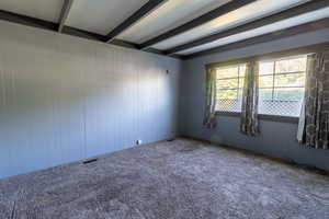 Carpeted living room featuring beamed ceiling and wood walls