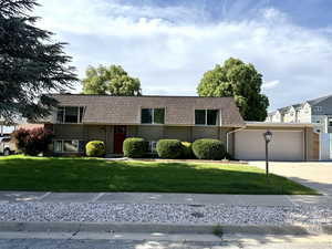 View of front of house featuring a garage, a front lawn, concrete driveway, mansard roof, and brick siding