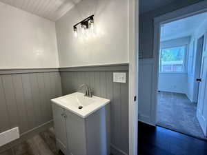 Bathroom with wood finished floors, a wainscoted wall, and vanity