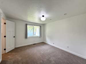 Carpeted spare room with baseboards and a textured ceiling