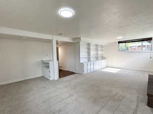 Carpeted spare room featuring a textured ceiling and baseboards